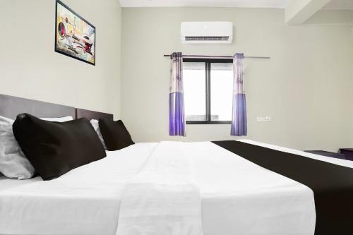 a bedroom with a white bed with purple curtains at Super Hotel O Rajendra Nagar Hingna Road in Nagpur