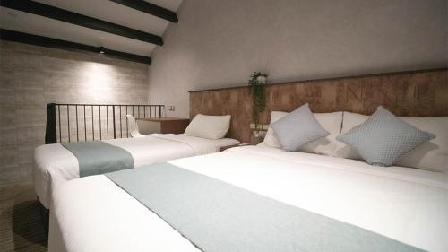 two beds in a hotel room with white sheets at Hotel Calmo Hamilton in Singapore