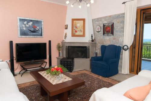 a living room with a tv and a blue chair at Seaside Serenity - Stylish Seaview Home in Kotrónion