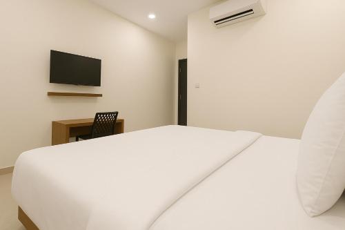 a bedroom with a white bed and a tv at Hotel Grand Stay Park Near Ameerpet Metro Station & GVK One Mall in Hyderabad
