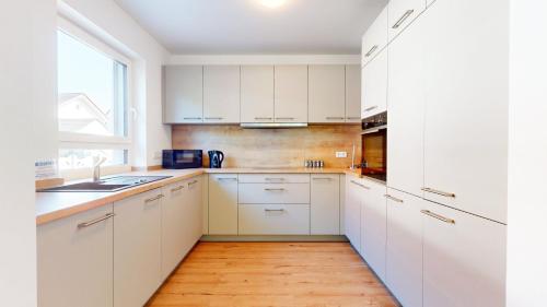 a kitchen with white cabinets and a wooden floor at TLA TDY Kurzzeitvermietung Haus in Kindsbach