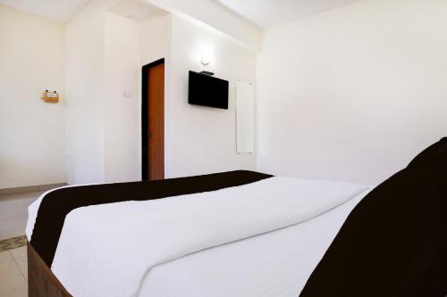 a bedroom with a white bed with a tv on the wall at Collection O Sand Castles Miramar in Goa