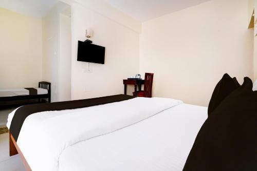 a bedroom with a white bed and a tv on the wall at Collection O Sand Castles Miramar in Goa