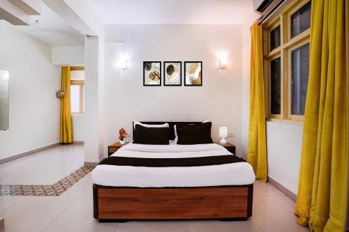 a bedroom with a large bed with yellow curtains at Collection O Sand Castles Miramar in Goa
