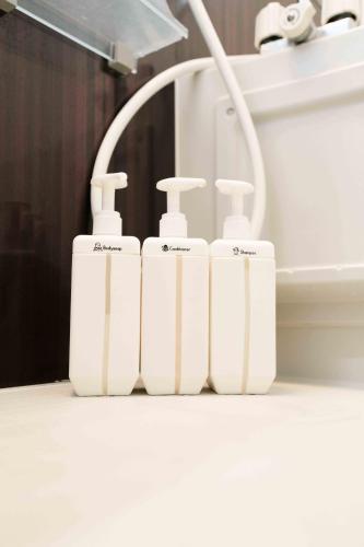 a group of four white soap dispensers in front of a mirror at 読谷波平2ベッドルームアパート海辺近く in Yomitan