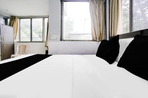 a white bed with black pillows in a room with windows at Super Collection O Andheri Near Mumbai Airport Formerly We Stay in Mumbai