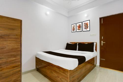 a bedroom with a bed with a wooden headboard at Super Hotel O Rajeev Nagar Formerly Happy Journey in Patna