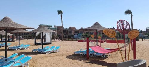 a beach with chairs and swings and umbrellas at بلو باي اسيا للعائلات فقط in Ain Sokhna