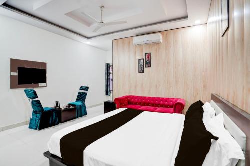 a bedroom with a bed and two chairs and a television at Super Townhouse Faizabad Road Opp BBD University in Lucknow