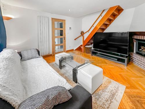 a living room with a couch and a television at Maison conviviale - Proche aéroport Roissy in Le Blanc-Mesnil