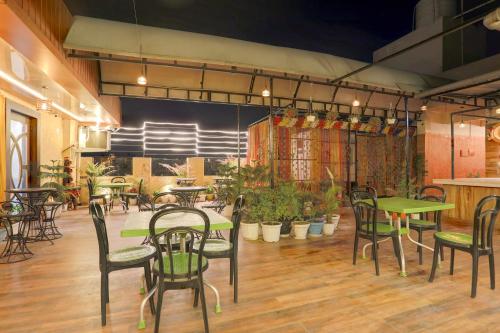 a restaurant with tables and chairs and plants at Super Townhouse Hyderabad Gate IIT BHU Formerly RK Heights in Varanasi