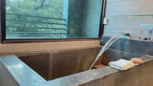 a bathroom with a tub with a water fountain at A-SAN Hot-Spring Hotel in Jiaoxi