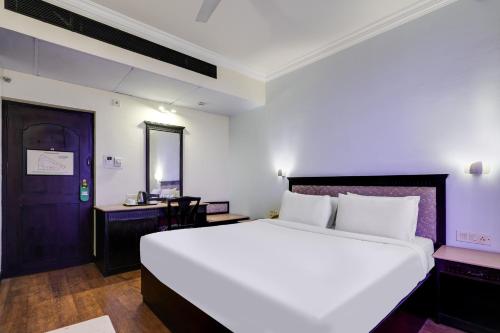 a bedroom with a large white bed and a desk at Palette MG Road Ernakulam Formerly Harbour View Residency in Cochin