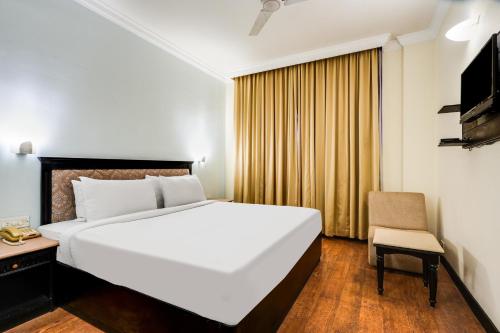 a bedroom with a large white bed and a chair at Palette MG Road Ernakulam Formerly Harbour View Residency in Cochin
