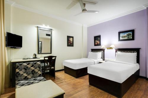 a hotel room with two beds and a desk at Palette MG Road Ernakulam Formerly Harbour View Residency in Cochin