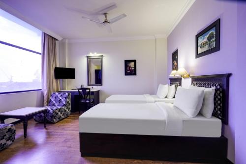 a hotel room with two beds and a chair at Palette MG Road Ernakulam Formerly Harbour View Residency in Cochin