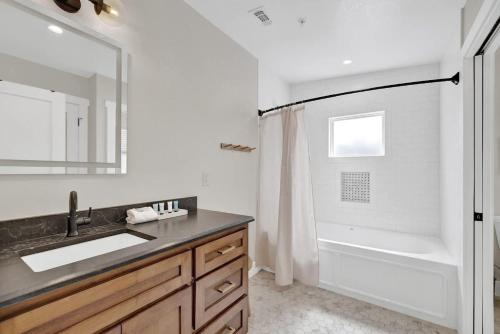 a bathroom with a sink and a tub and a mirror at The Grove-A: Cozy Cottage 2-Blocks to Marktplatz! in Fredericksburg