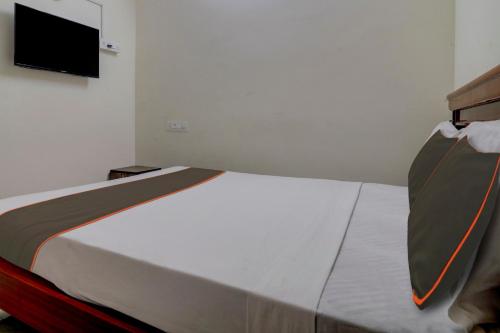 a bed in a room with a tv on the wall at Super Collection O Manikonda in Hyderabad