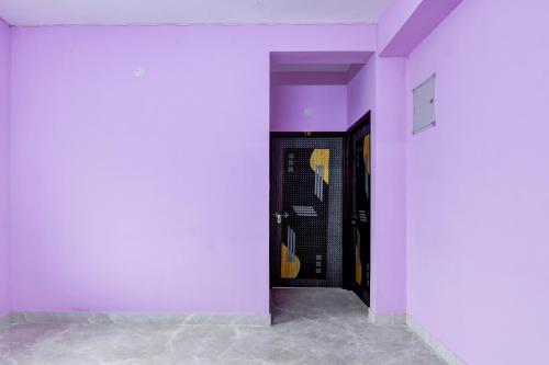 a hallway with purple walls and a black door at Hotel O Uniworld Formerly Cubic Palace in kolkata