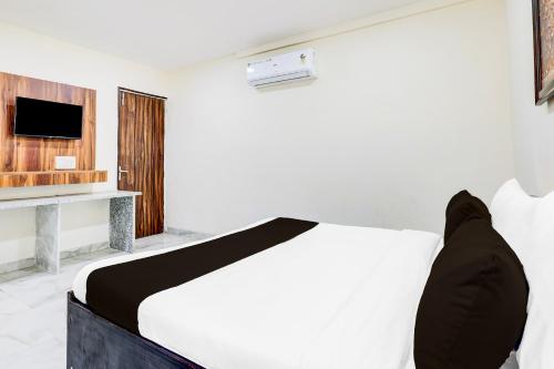 a bedroom with a white bed and a television at Super Hotel O Sector 25 Near Iskcon Temple Formerly Hotel Amazing House in New Delhi