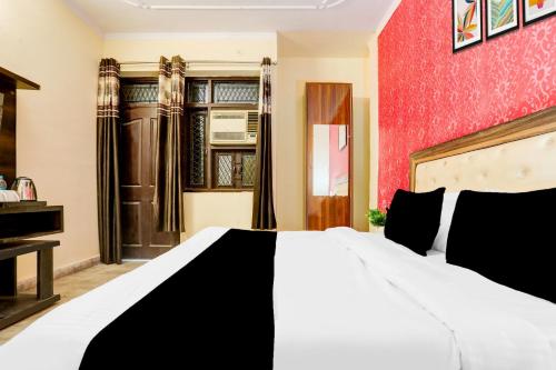 a bedroom with a white bed and a red wall at Super Hotel O Uttam Nagar Near Akash Hospital in New Delhi