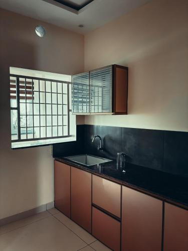 a kitchen with brown cabinets and a black counter top at Azay Luxurious Apartment in Kalpetta