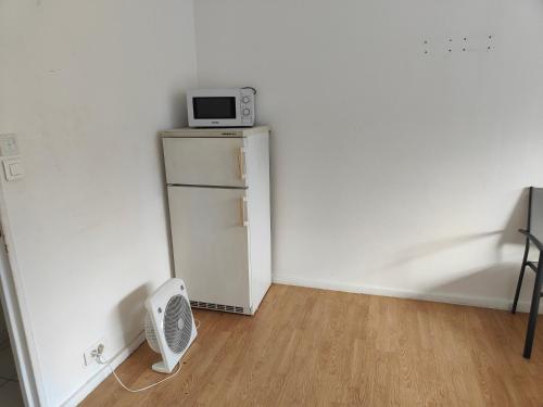 an empty room with a microwave on top of a refrigerator at Guest home in Sarcelles