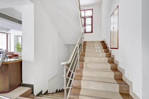 a staircase in a home with white walls and wooden floors at Collection O M G Road in Trivandrum