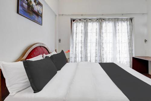 a bedroom with a large white bed and a window at Collection O M G Road in Trivandrum