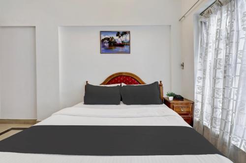 a bedroom with a large white bed and curtains at Collection O M G Road in Trivandrum