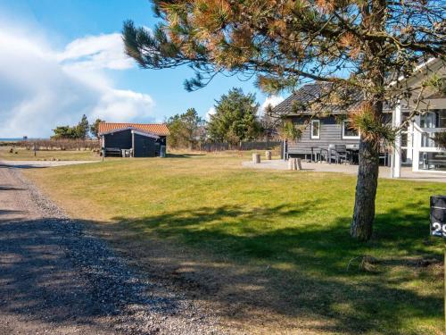 a house and a tree in front of a field at 10 person holiday home in Løgstør-By Traum in Trend