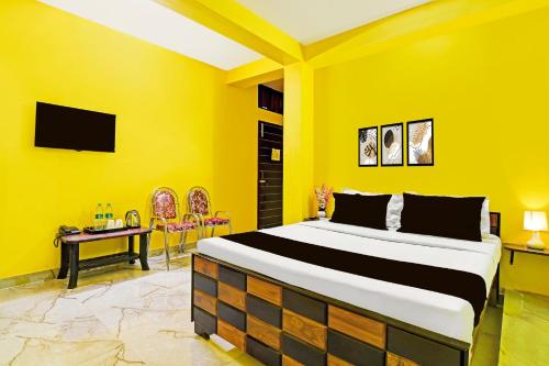 a yellow bedroom with a bed and a desk at Super Hotel O Kabardanga More Kolkata Formerly Royal Crown Banquet in Taliganja