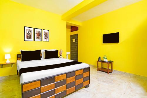 a yellow room with a bed and a tv at Super Hotel O Kabardanga More Kolkata Formerly Royal Crown Banquet in Taliganja