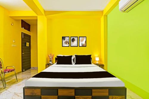 a bedroom with a large bed with yellow walls at Super Hotel O Kabardanga More Kolkata Formerly Royal Crown Banquet in Taliganja
