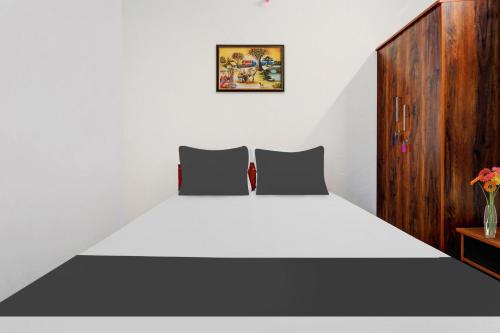 a bedroom with a white bed and a wooden cabinet at Super Hotel O Okkilipalayam in Coimbatore