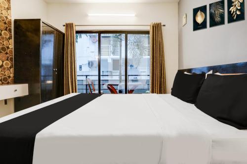 a bedroom with a large white bed and a window at Super Collection O Morjim in Goa
