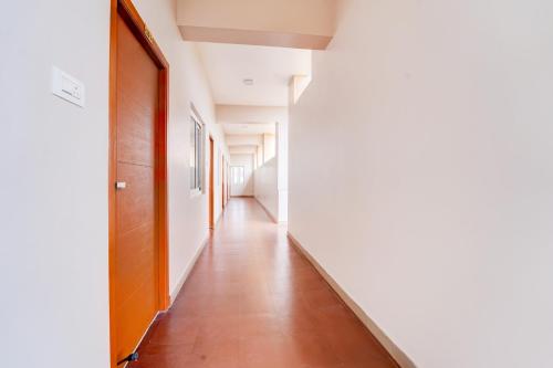an empty hallway with white walls and a wooden door at Super Collection O Karumathampatti in Coimbatore