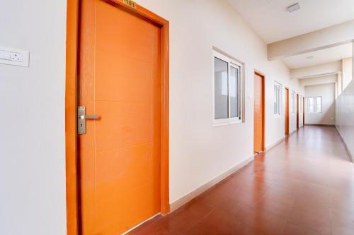 an empty hallway with an orange door and white walls at Super Collection O Karumathampatti in Coimbatore