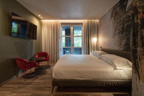a bedroom with a bed and a window and a chair at Phi Hotel Piajo in Nembro