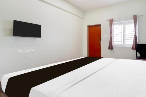 a bedroom with a bed and a tv on the wall at Super Collection O Karumathampatti in Coimbatore