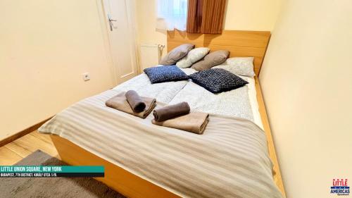 a bed with three pillows and towels on it at Little New York West Side Apartments in Budapest