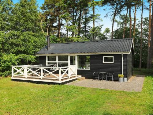 a black tiny house with a large porch at 4 person holiday home in Hadsund in Hadsund