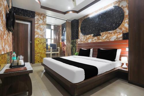 a bedroom with a large white bed and a desk at Super Collection O Tikonia in Haldwāni