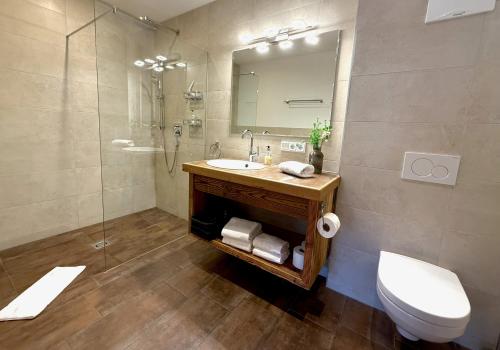 a bathroom with a sink and a toilet and a mirror at CHALET BELLE KAISER by Belle Stay in Going