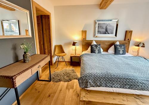 a bedroom with a bed and a table and a mirror at CHALET BELLE KAISER by Belle Stay in Going