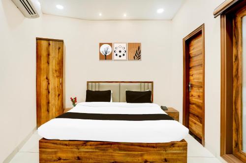 a bedroom with a large white bed with a wooden headboard at Super Collection O City Center Ludhiana Formerly MMC Inn in Ludhiana