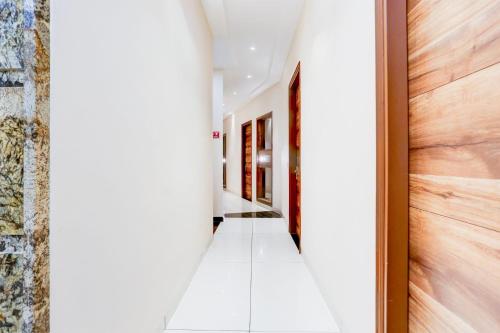 a hallway with white tile floors and wooden doors at Super Collection O City Center Ludhiana Formerly MMC Inn in Ludhiana