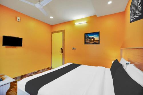 a bedroom with a bed with orange walls and a tv at Super Collection O Kushal Nagar Near KSRTC Bus Stand in Madikeri