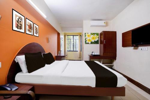 a bedroom with a large bed with an orange wall at Super Collection O Hubli City Center Formerly Chalukya Residency in Hubli