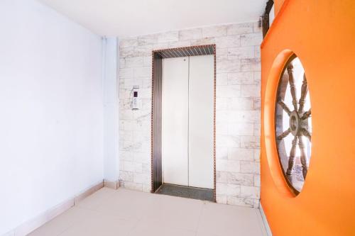 an orange hallway with a door and a mirror at Super Collection O Hubli City Center Formerly Chalukya Residency in Hubli